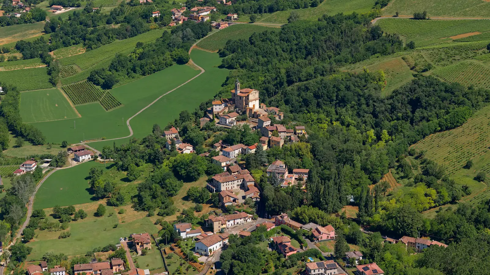 Paese con campanile tra colline e campi